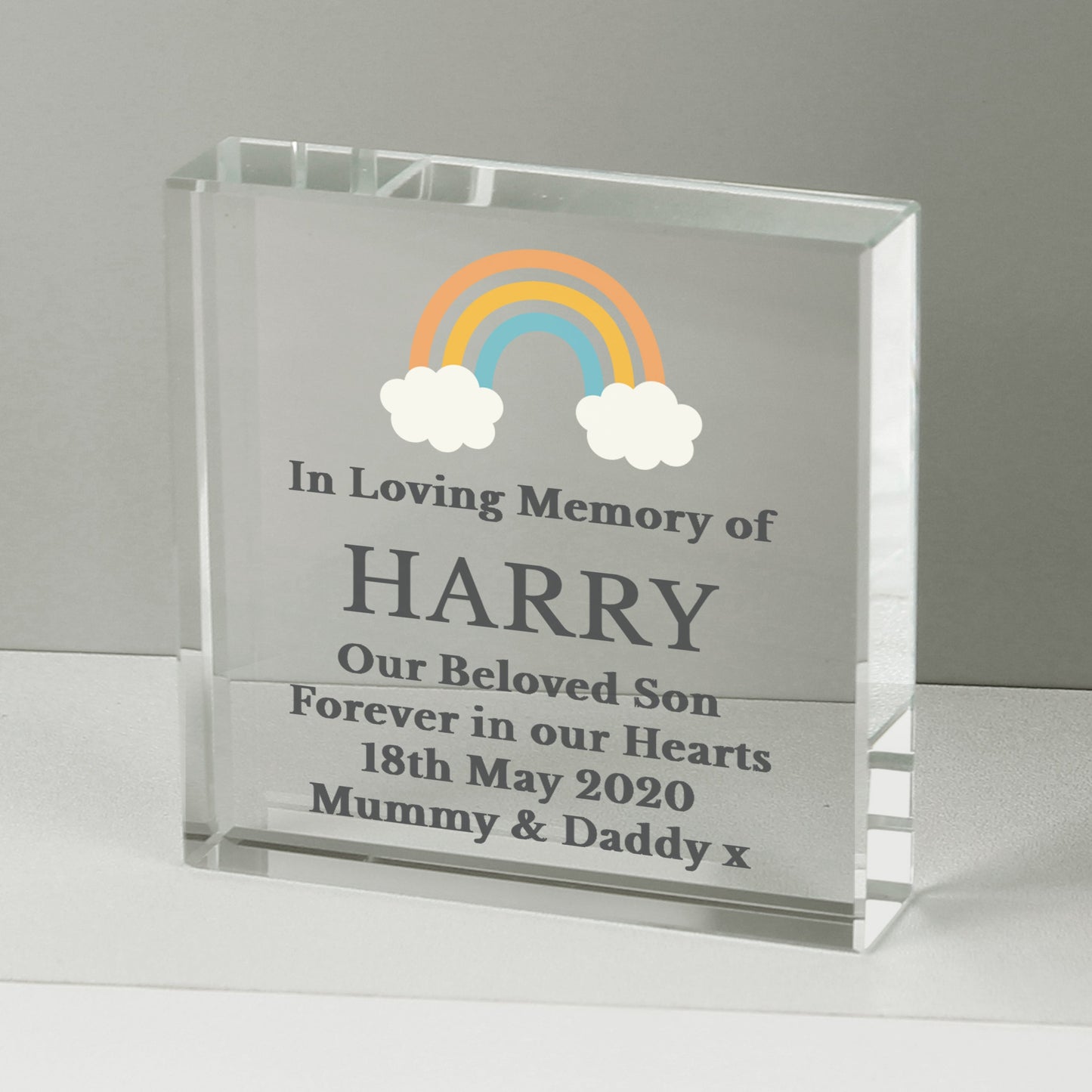 a clear glass block with a rainbow and clouds on it