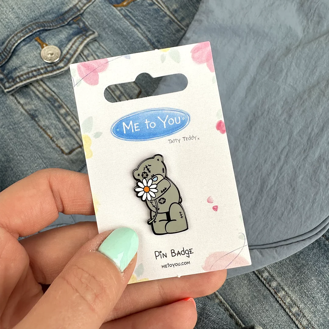 a person holding a pin with a bear on it