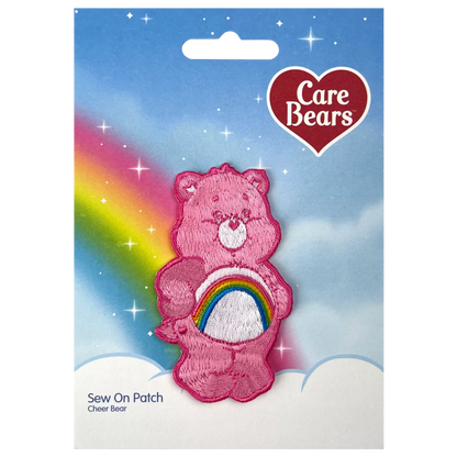 a pink teddy bear with a rainbow in the background