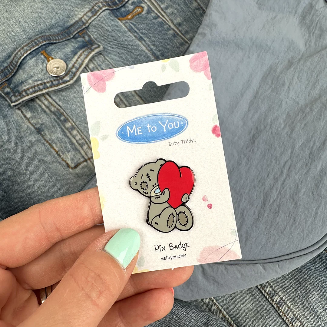 a person holding a pin with a picture of a teddy bear on it