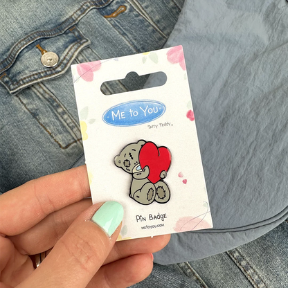 a person holding a pin with a picture of a teddy bear on it