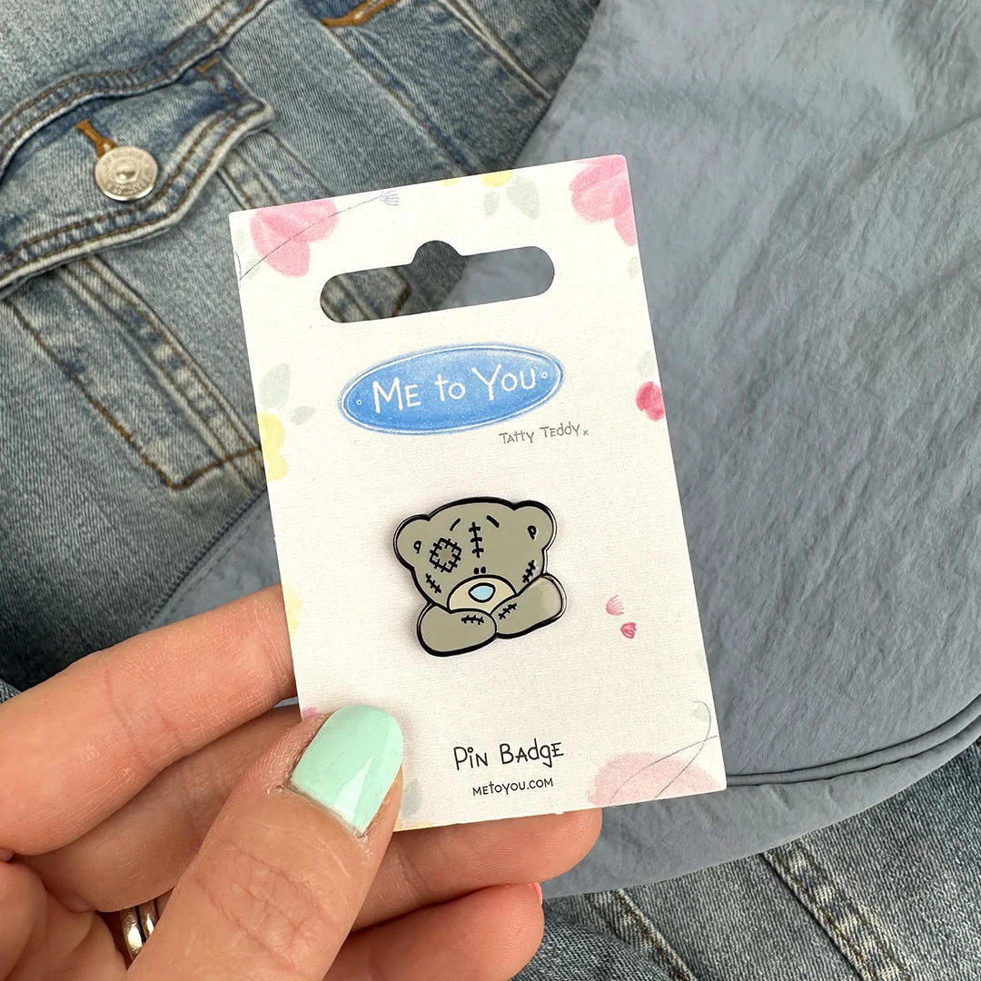 a person holding a pin with a teddy bear on it