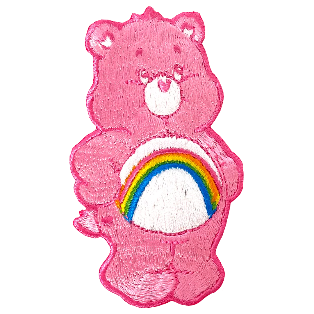 a pink teddy bear with a rainbow patch