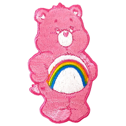 a pink teddy bear with a rainbow patch