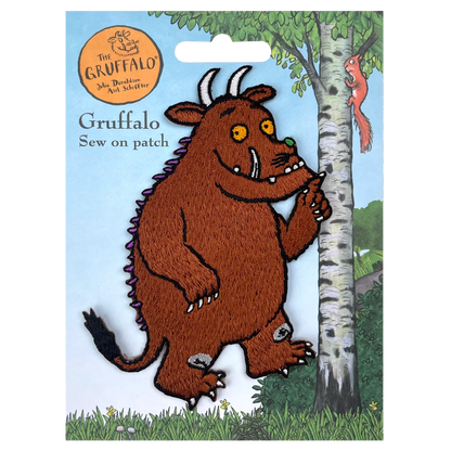 a felt picture of a brown troll standing next to a tree
