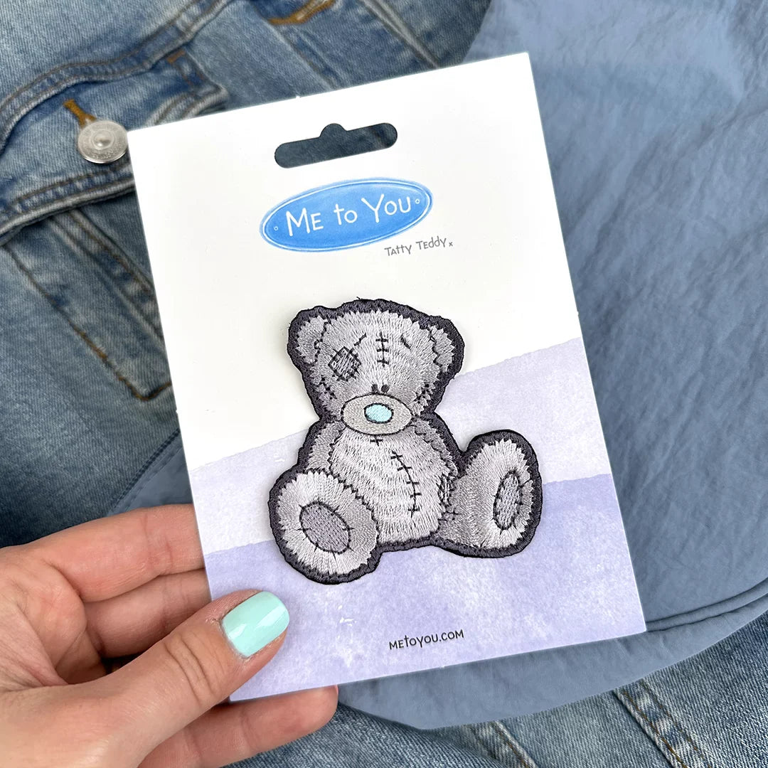 a person holding a sticker of a teddy bear