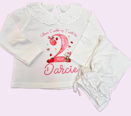 White baby outfit with pink text and design on a pink grid background